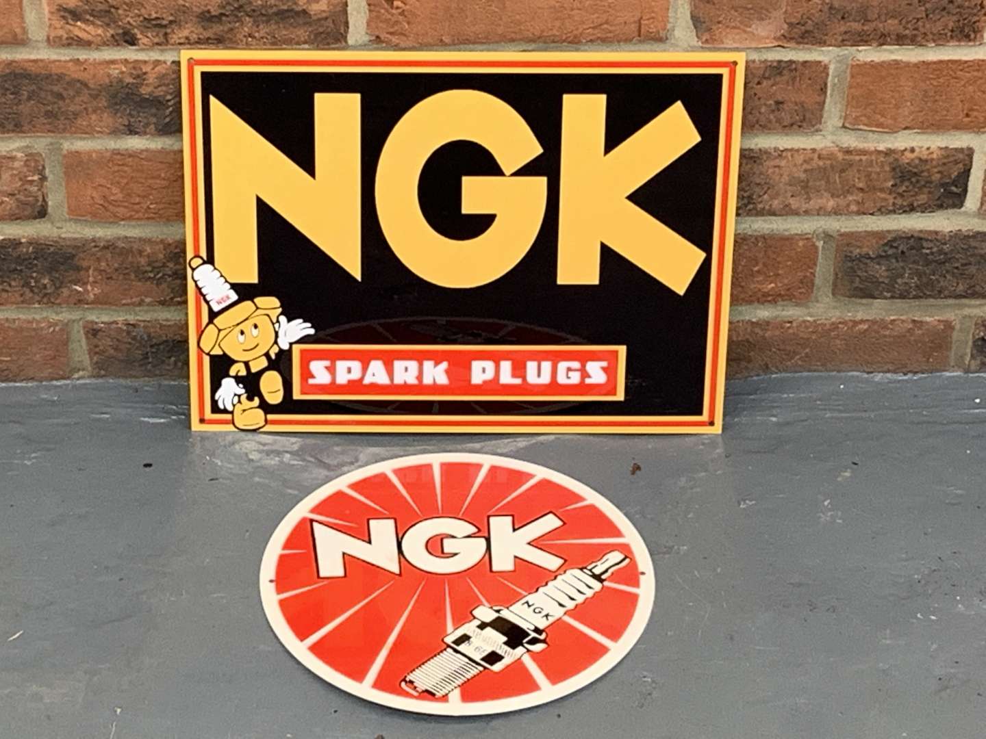 <p>Two Metal NGK Spark Plug Signs</p>