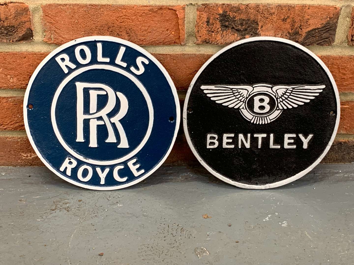<p>Two Cast Iron Bentley and Rolls Royce Circular Signs</p>
