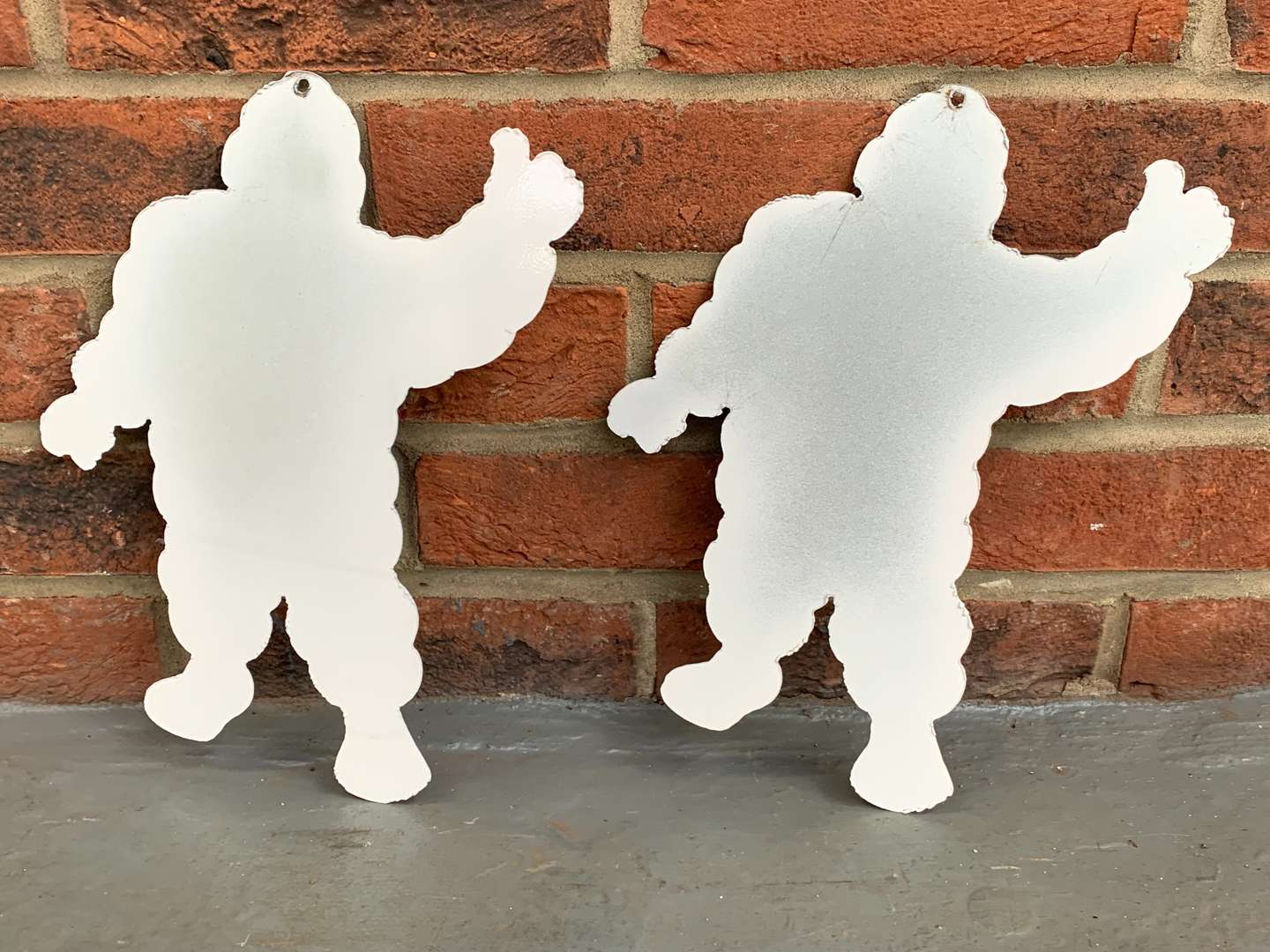 <p>Two Metal Small Michelin Men Signs</p>