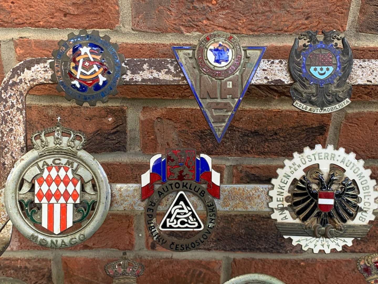 <p>A Significant Collection of Pre-War Badges on a Bar</p>