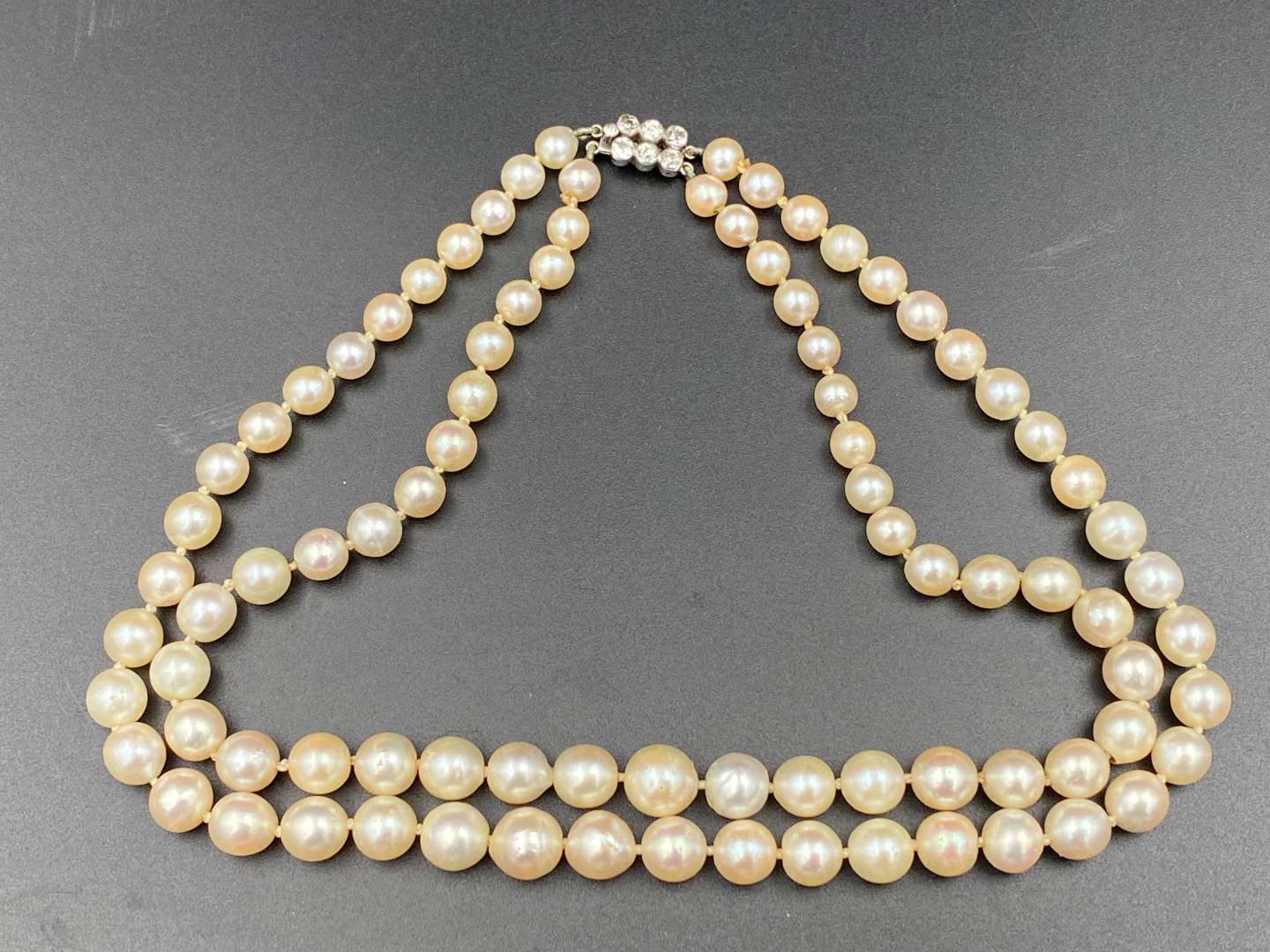 <p>Twin strand of graduated, cultured pearls, with diamond clasp set with six old cut stones.</p>