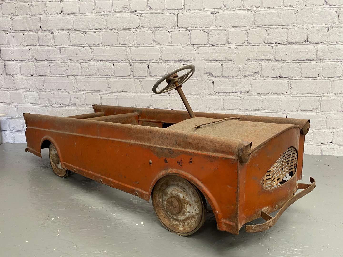 <p>A mid 20th century pressed steel pedal car,</p>