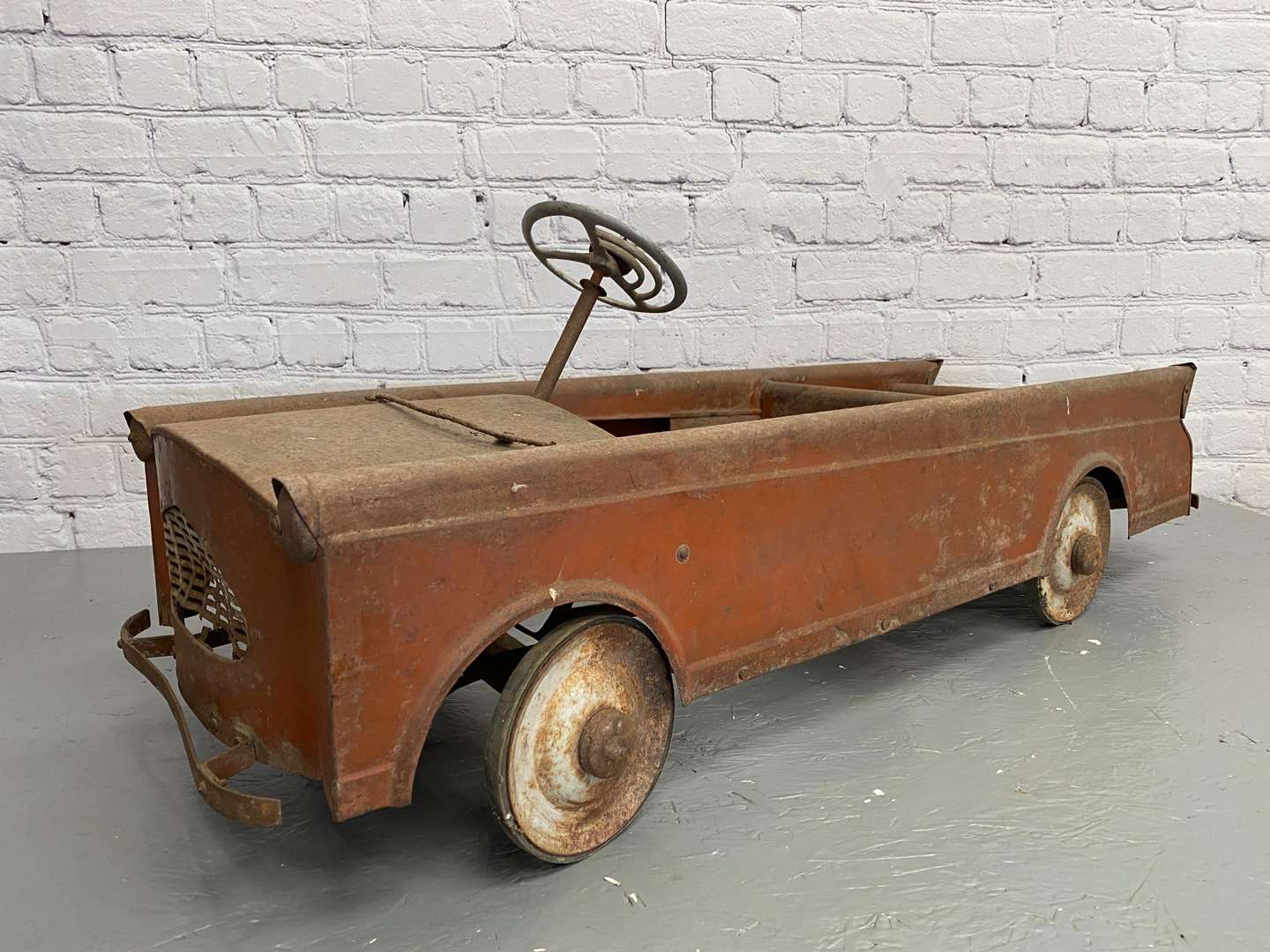 <p>A mid 20th century pressed steel pedal car,</p>