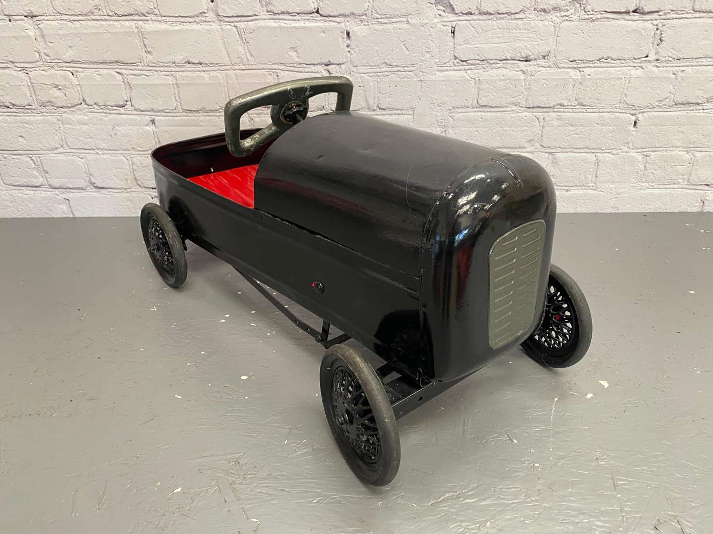 <p>A mid 20th century pressed steel pedal car,&nbsp;</p>
