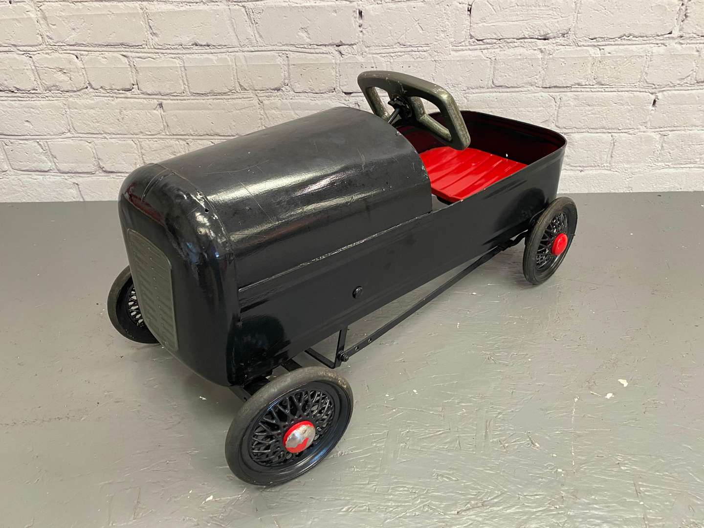 <p>A mid 20th century pressed steel pedal car,&nbsp;</p>