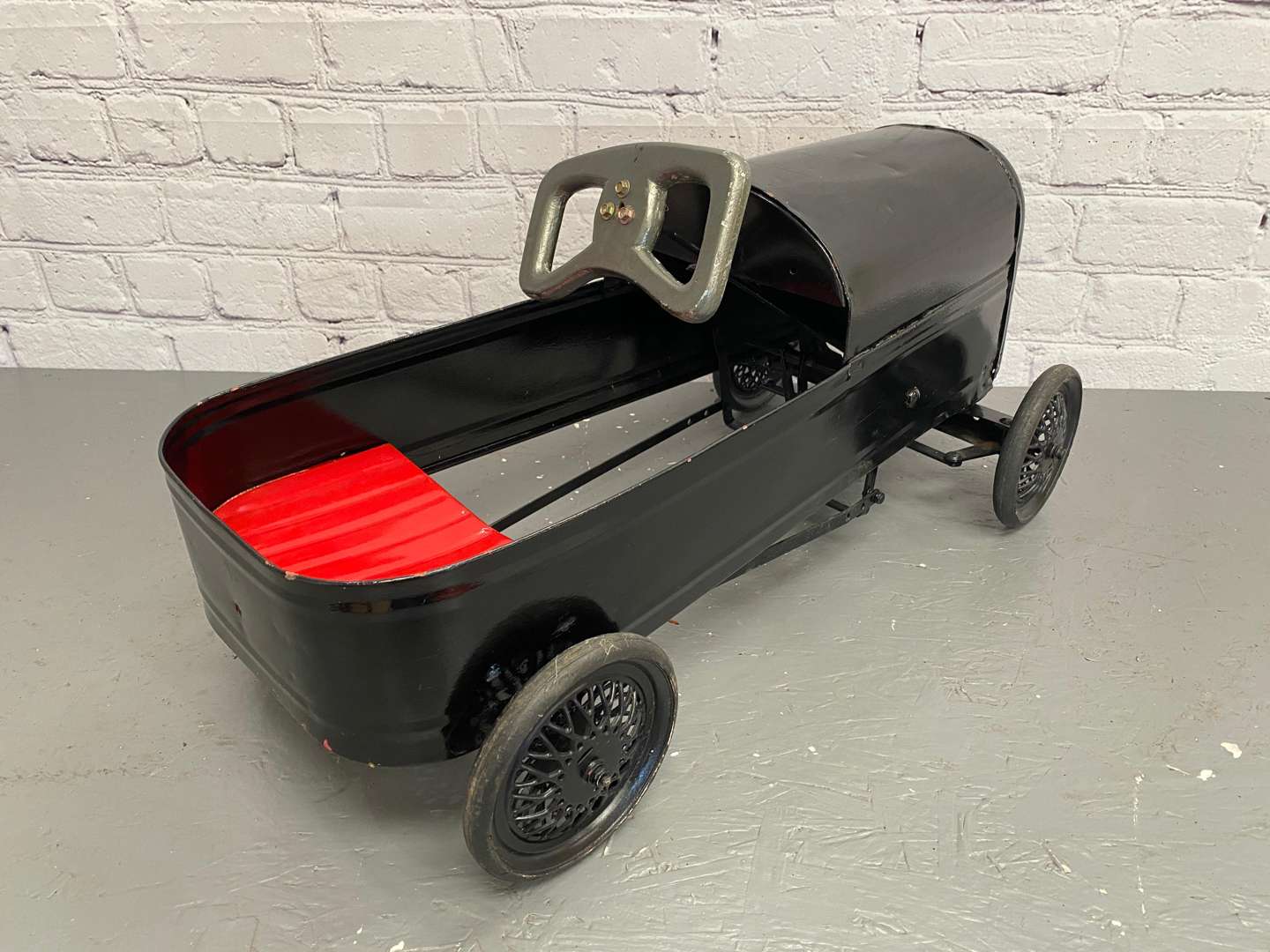 <p>A mid 20th century pressed steel pedal car,&nbsp;</p>