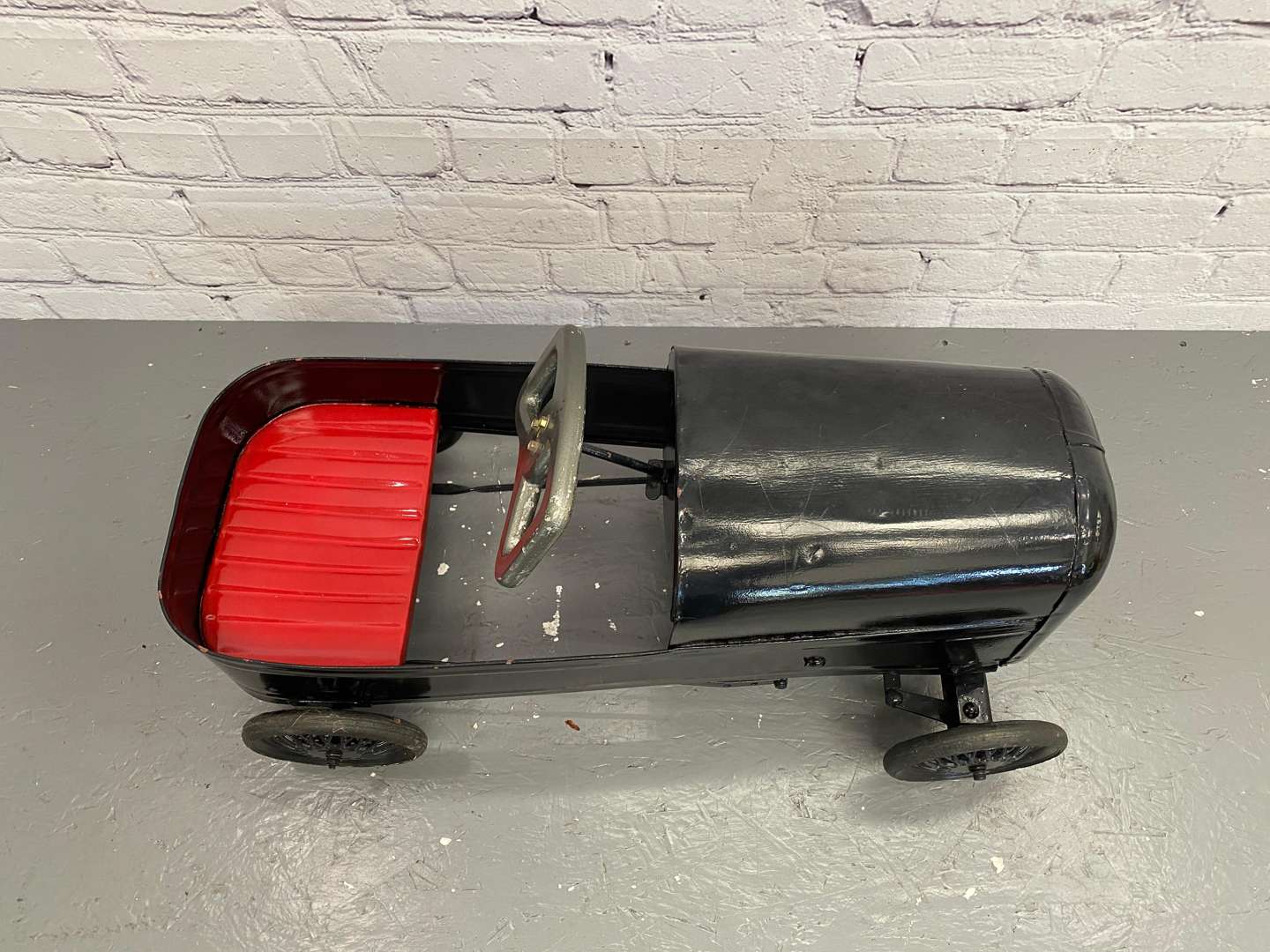 <p>A mid 20th century pressed steel pedal car,&nbsp;</p>