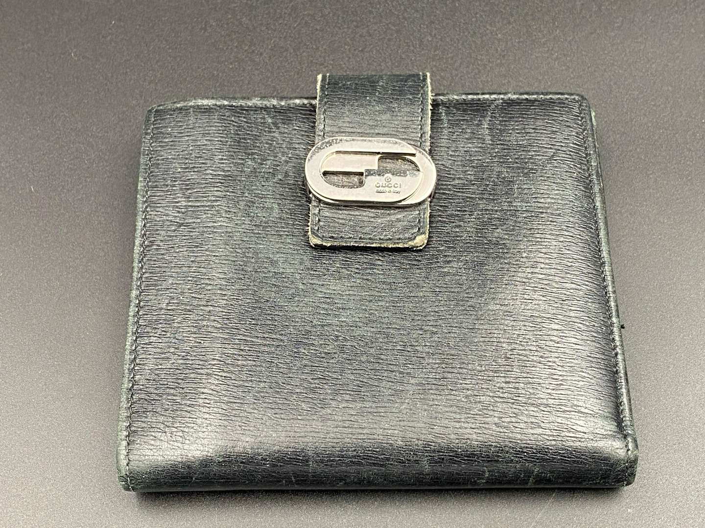 <p>GUCCI, &nbsp;a black, grained, leather wallet with signed and polished clasp</p>