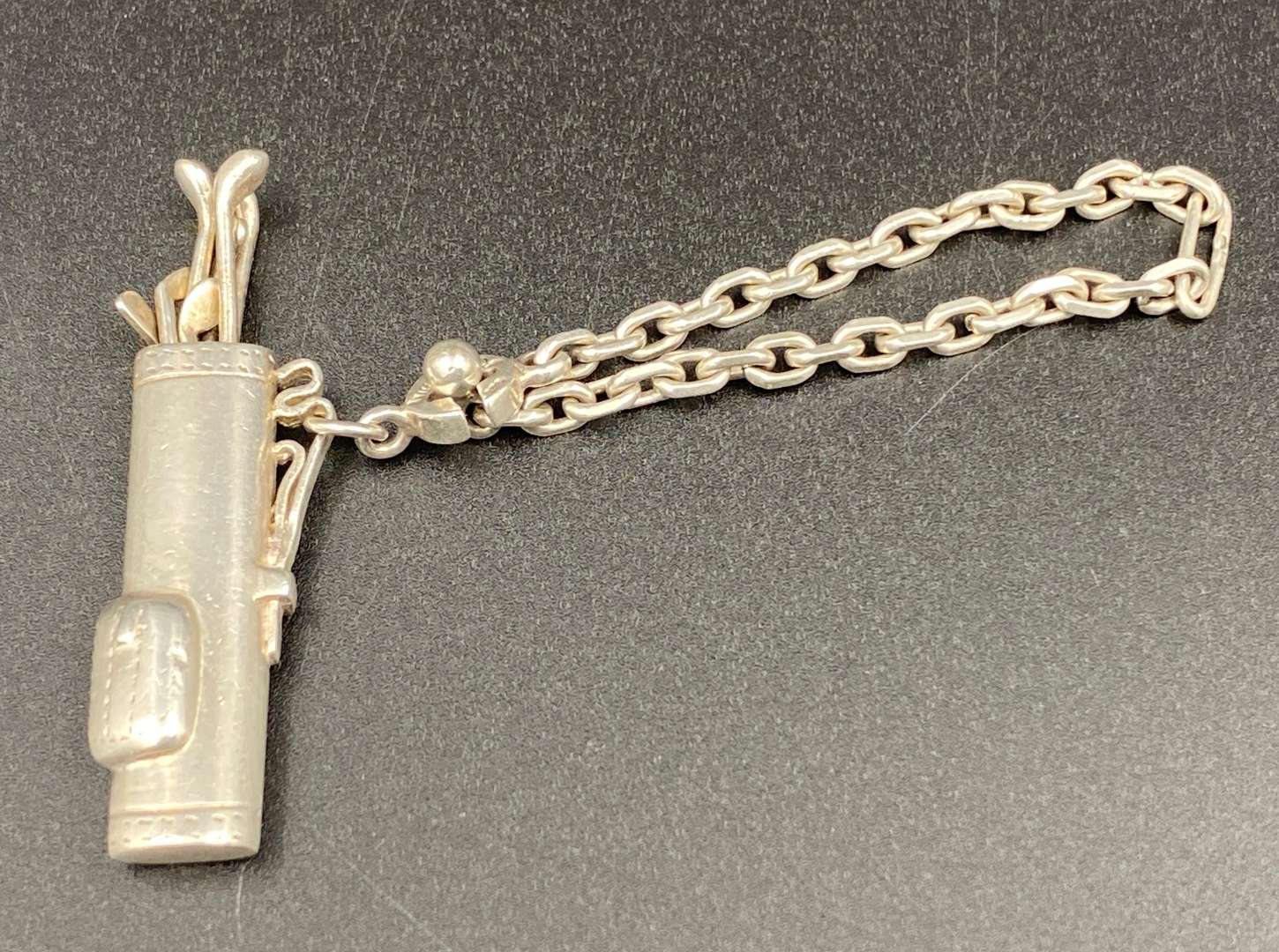 <p>A novelty white metal golf bag, button hole/ key chain,</p>