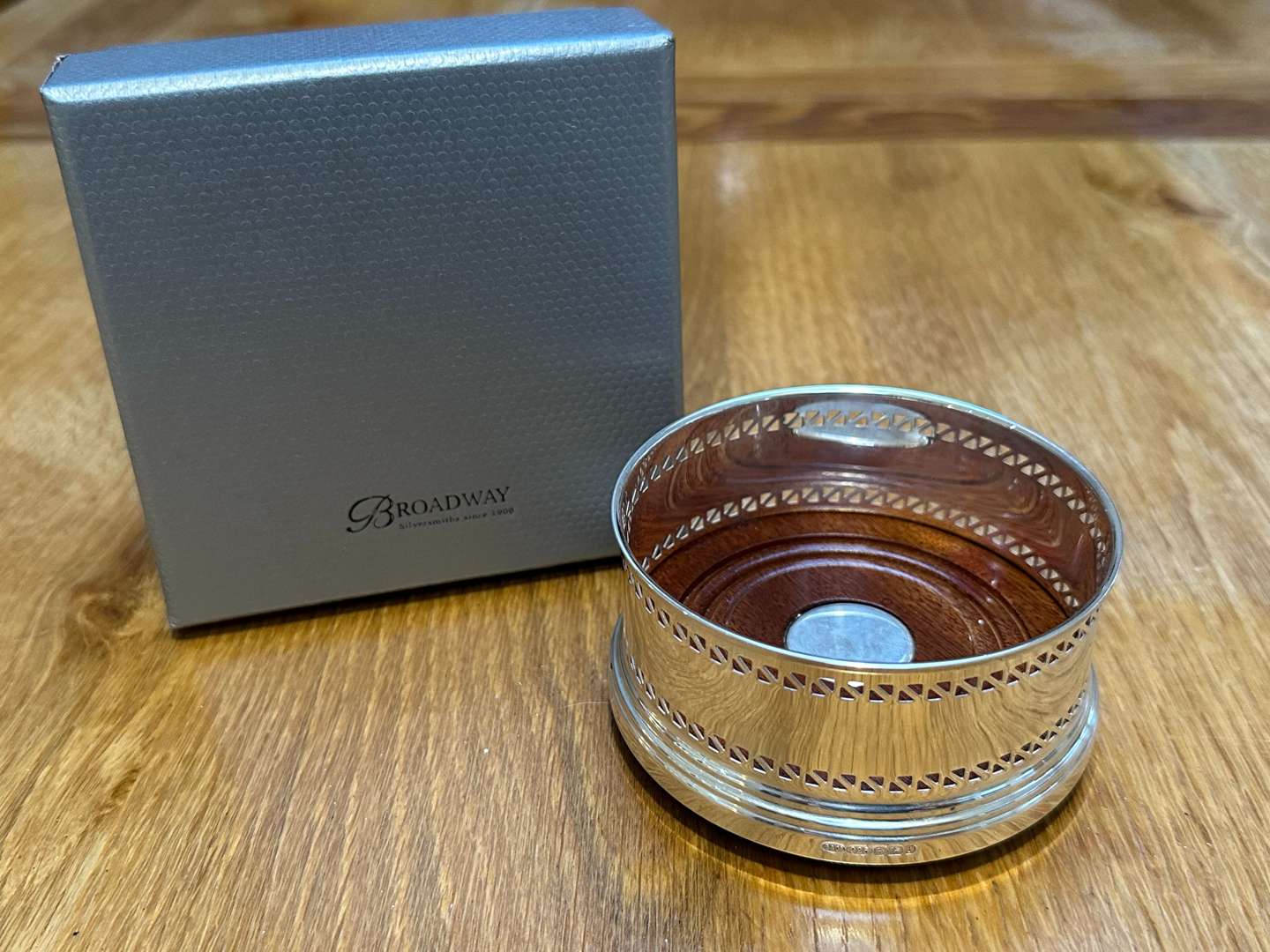 <p>BROADWAY & Co, an Elizabeth II hallmarked silver and mahogany bottle coaster&nbsp;</p>