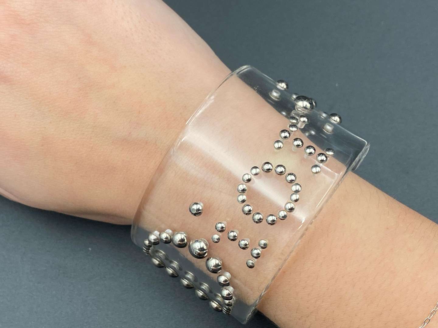 <p>CHRISTIAN DIOR, signed perspex and silvered studded cuff bracelet</p>