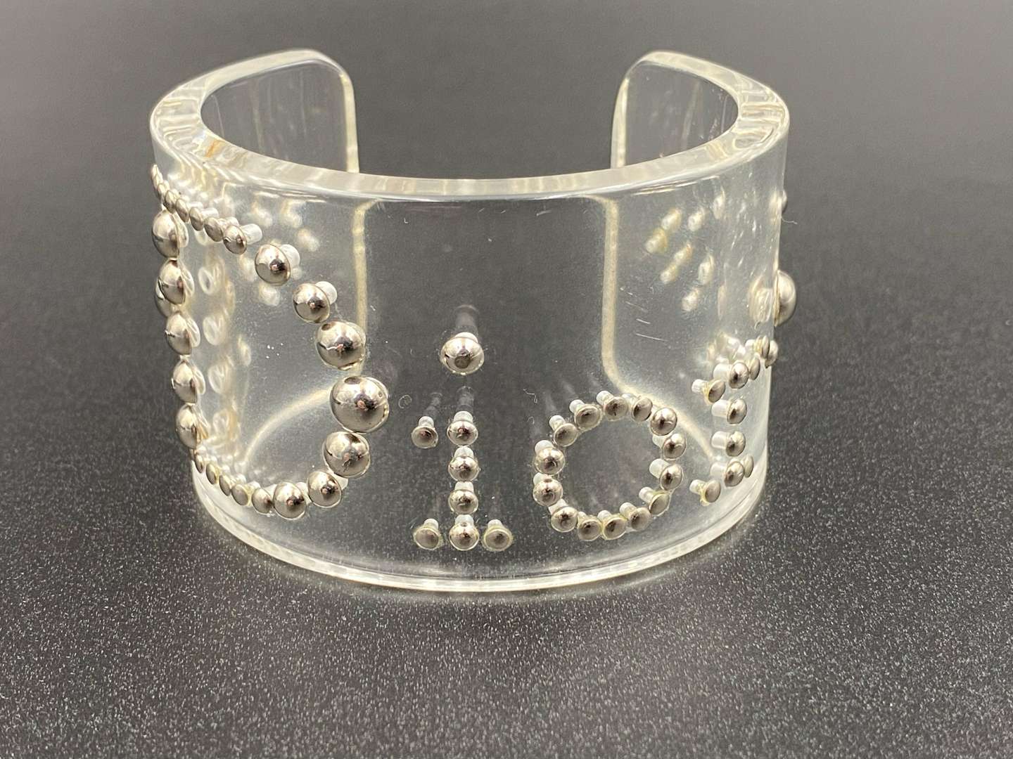 <p>CHRISTIAN DIOR, signed perspex and silvered studded cuff bracelet</p>