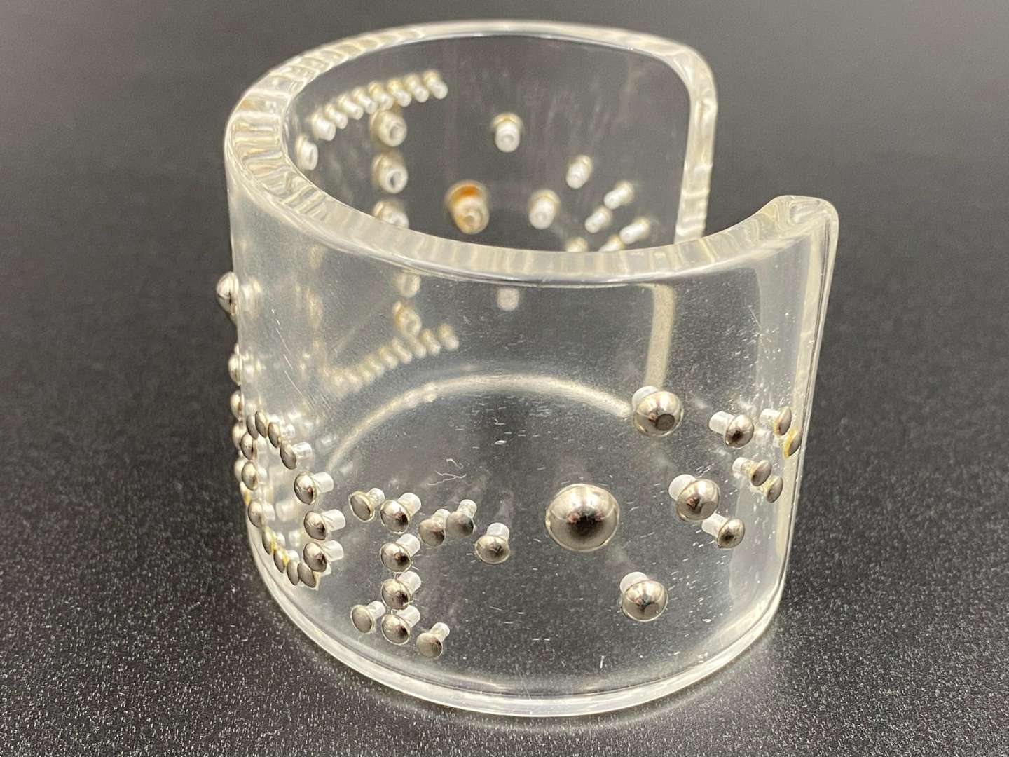 <p>CHRISTIAN DIOR, signed perspex and silvered studded cuff bracelet</p>
