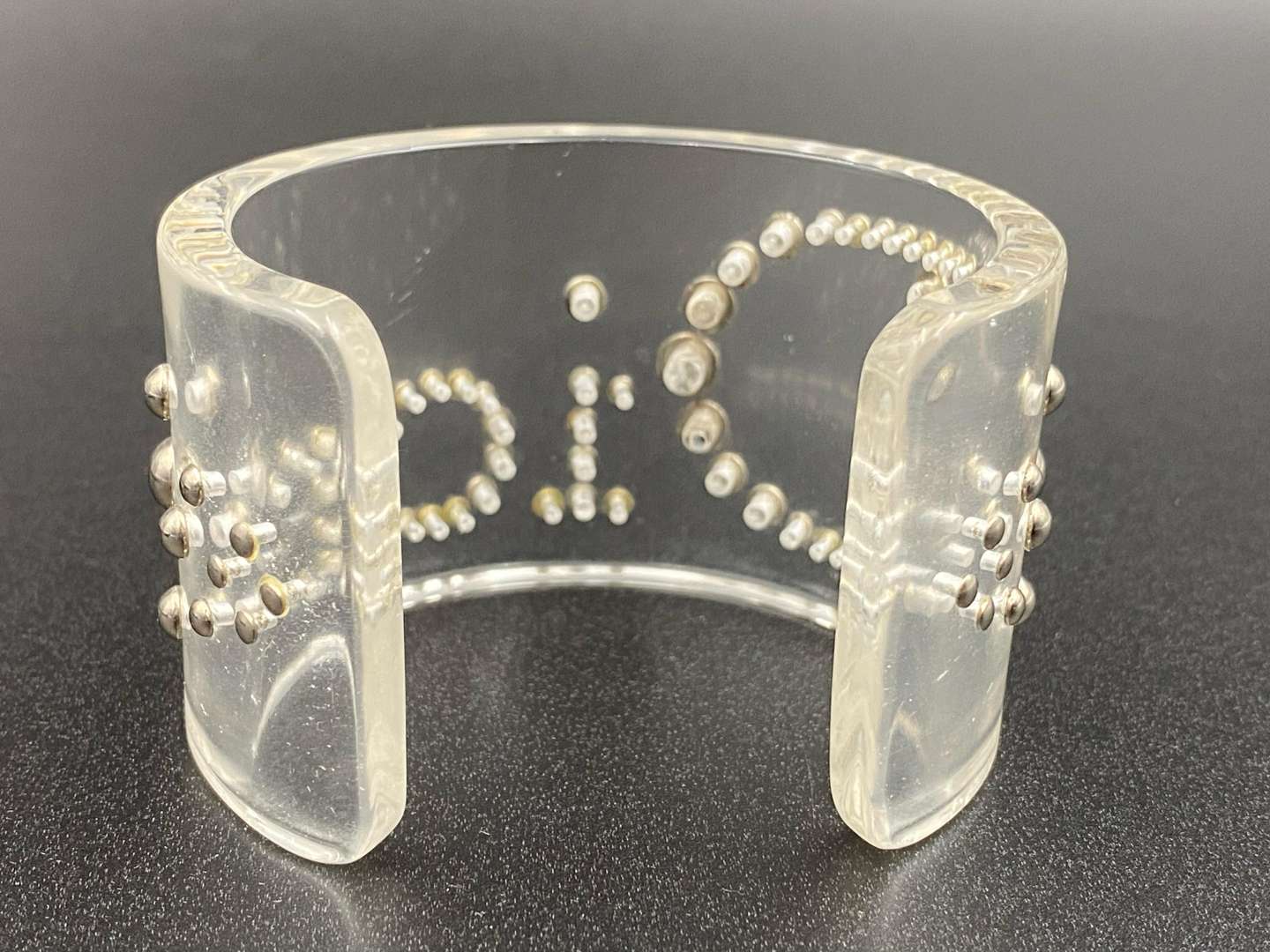 <p>CHRISTIAN DIOR, signed perspex and silvered studded cuff bracelet</p>