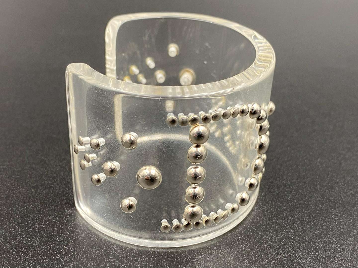 <p>CHRISTIAN DIOR, signed perspex and silvered studded cuff bracelet</p>